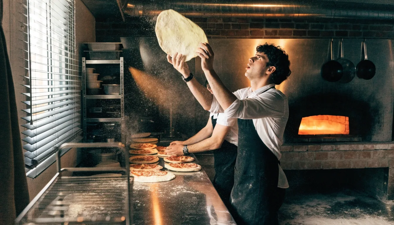 Hands tossing fresh pizza dough in a Fireaway kitchen
